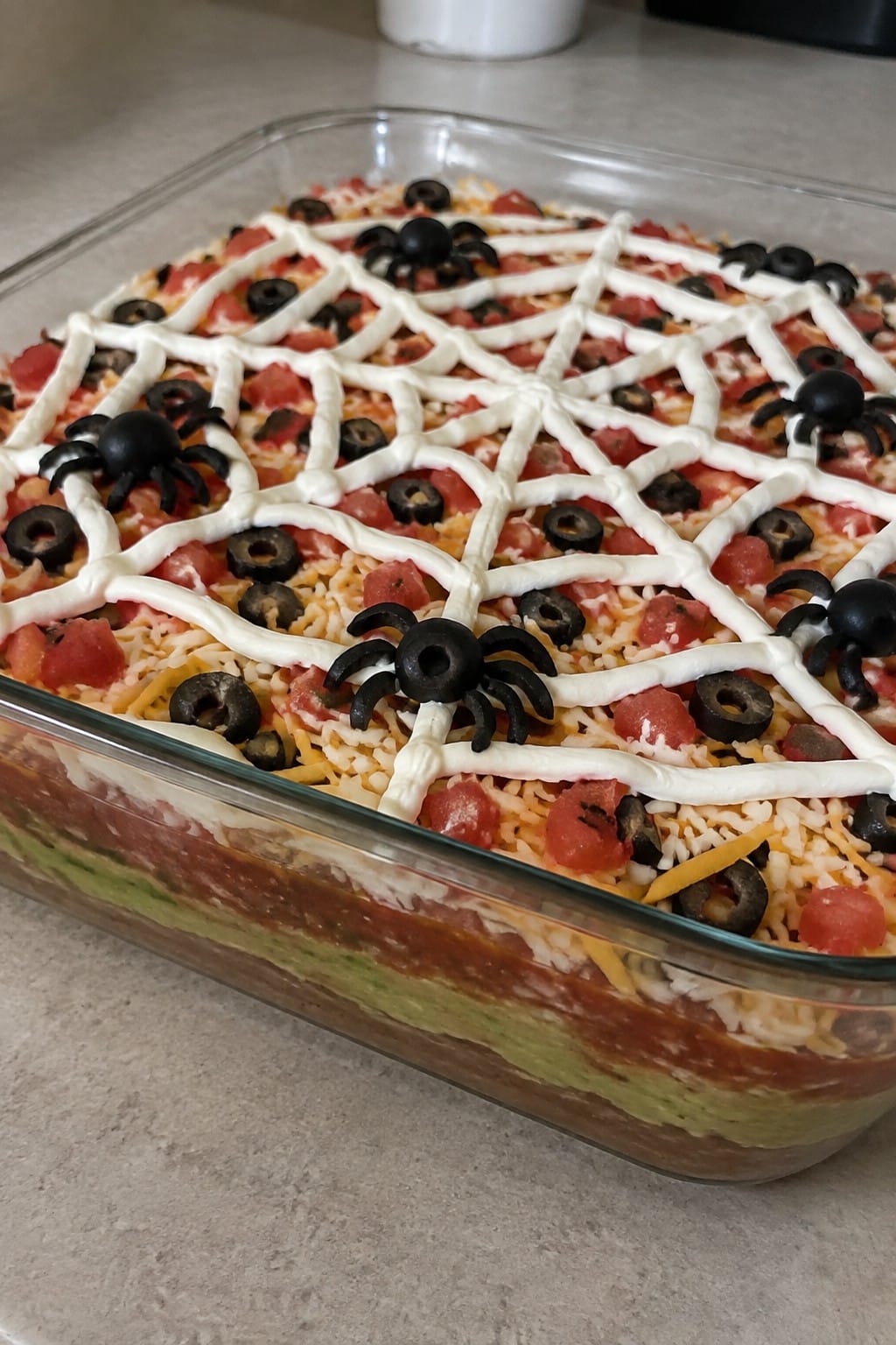 Spooky Seven-Layer Taco Dip with Sour Cream Spiderweb