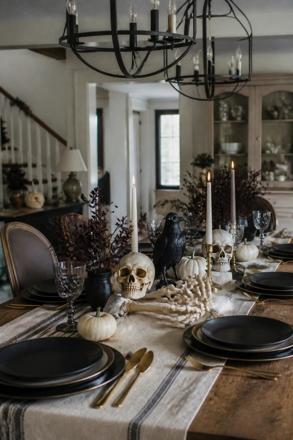 Elegant Halloween table with skulls, black crow, white pumpkins, skeleton, and candles