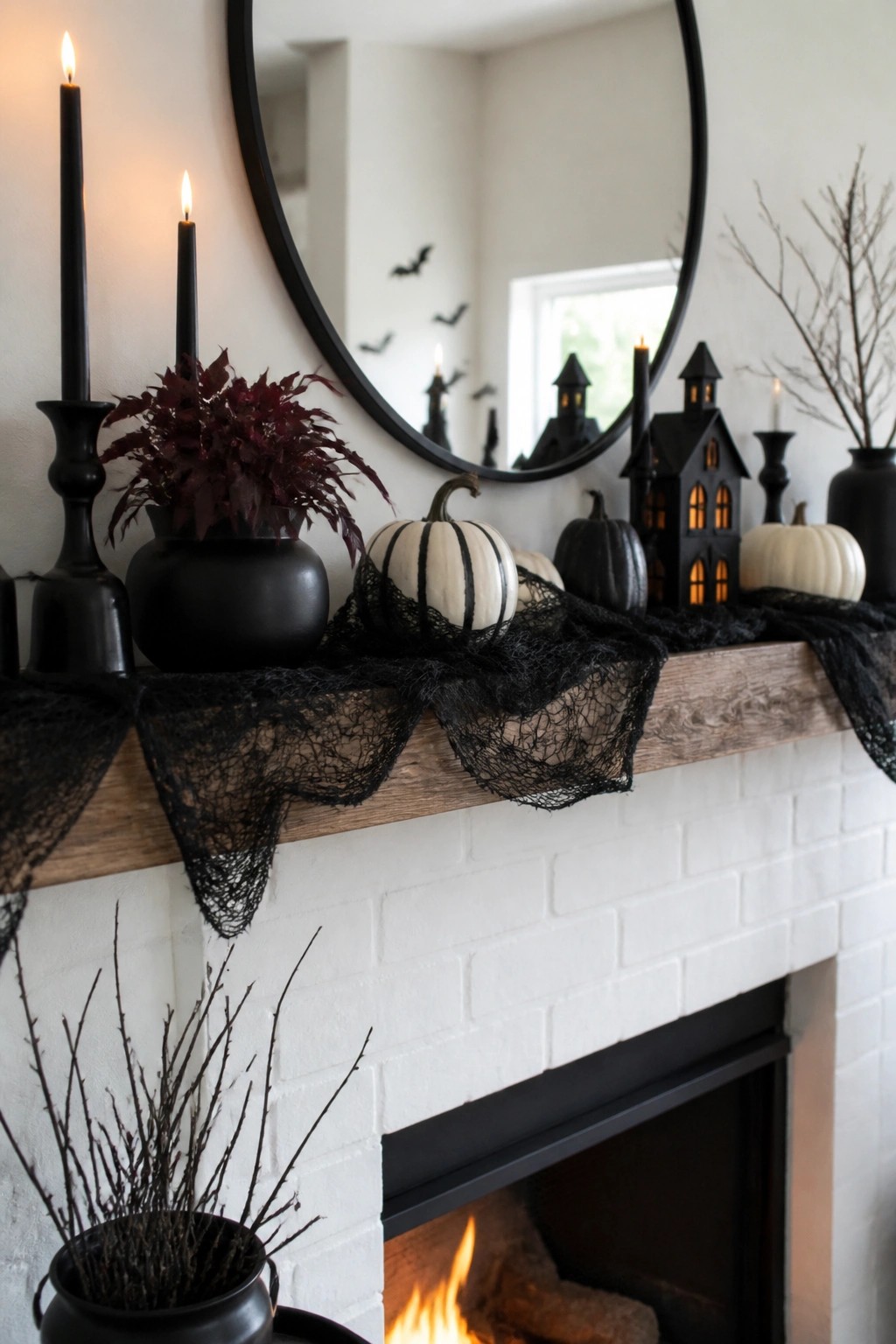 A white brick fireplace mantel styled for Halloween with black lace fabric, assorted pumpkins, black candles, and miniature haunted houses.